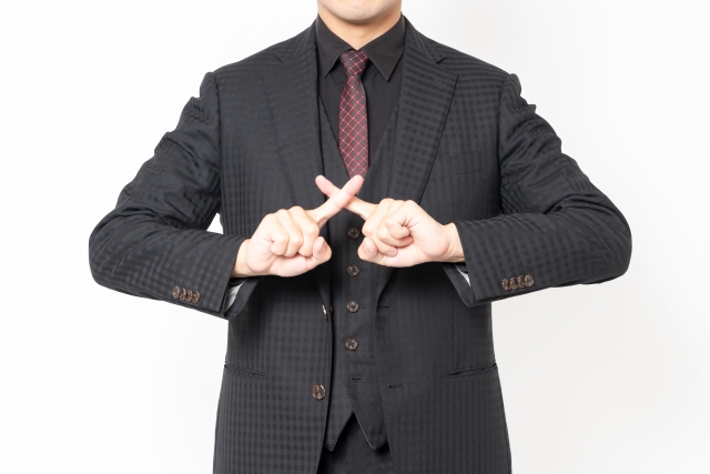 指でバツマークをする男性"