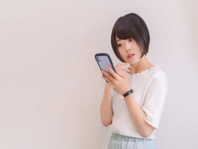 スマホを見ながら疑う女性
